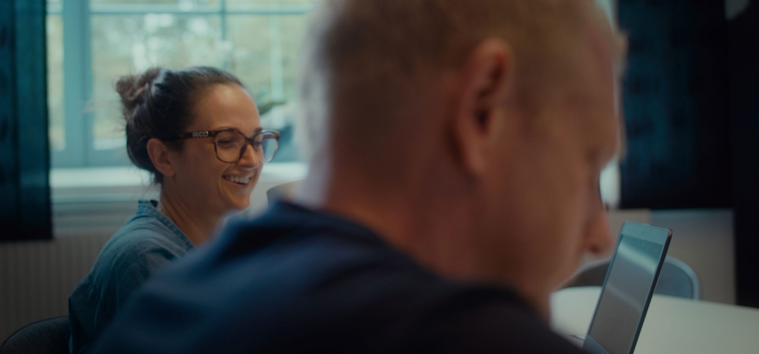 Hero Image Conversation held between smiling person in background in focus and out of focus person in foreground