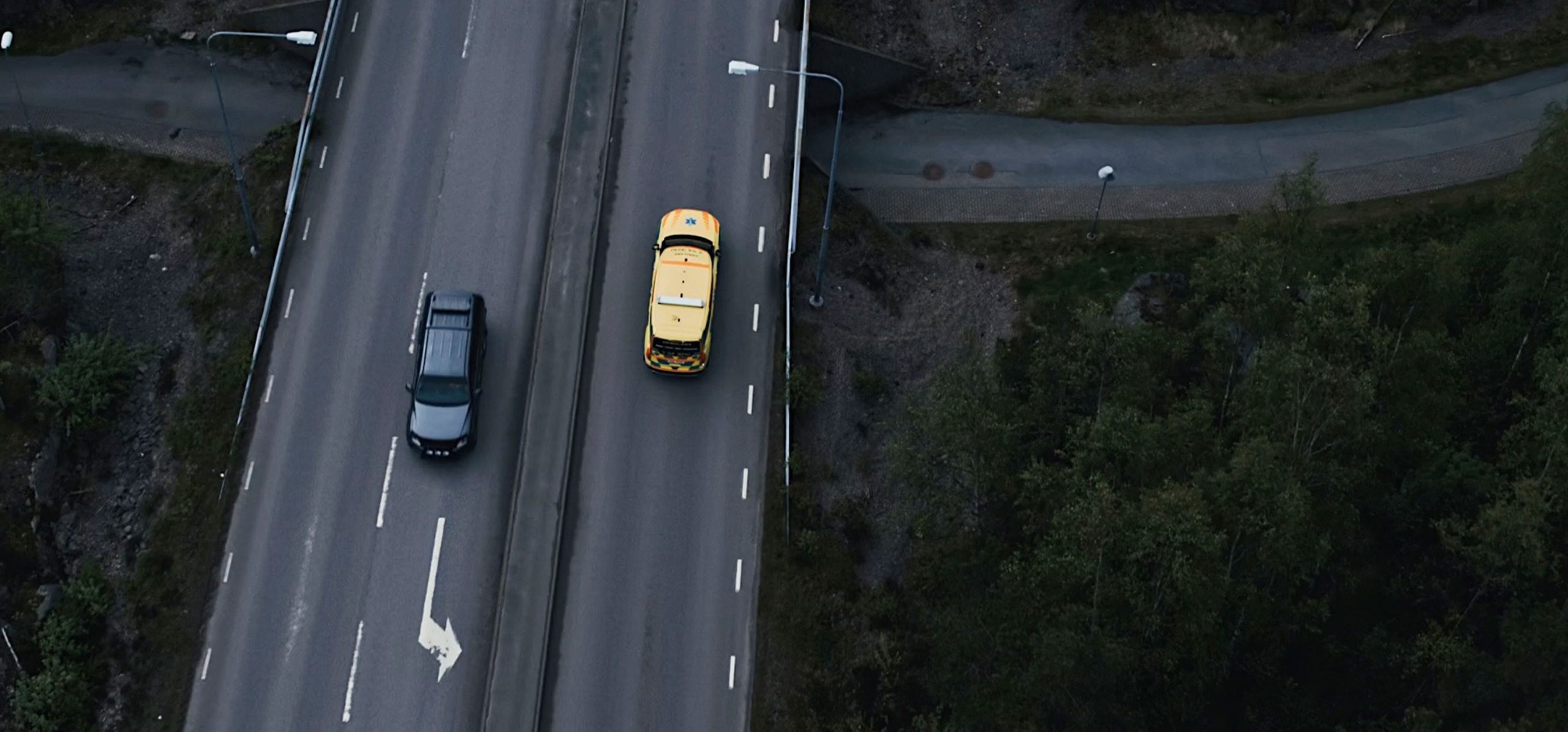 Hero Image Aerial Motorway Shot Yellow Emergency Vehicle and Black Car Driving in Opposite Directions, Road and Underpass are Dark